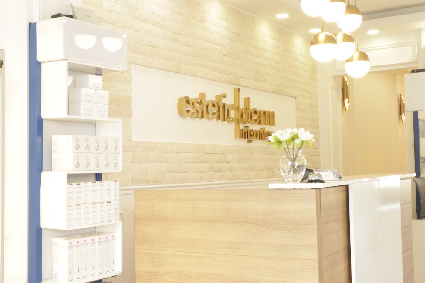 EsteticDerm Clinic Istanbul — pirinç aydınlatmalı, taş duvarlı karşılama alanı